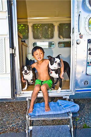 Boy sitting in door of camper with dogs Foto de stock - Sin royalties Premium, Código: 673-03405747