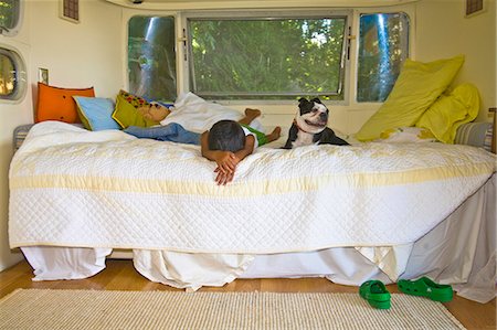 Boy and dog on bed in camper Foto de stock - Sin royalties Premium, Código: 673-03405773