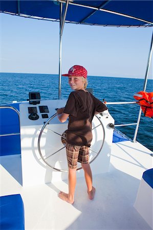 pleasure boat - boy steering yacht Stock Photo - Premium Royalty-Free, Code: 673-03826261