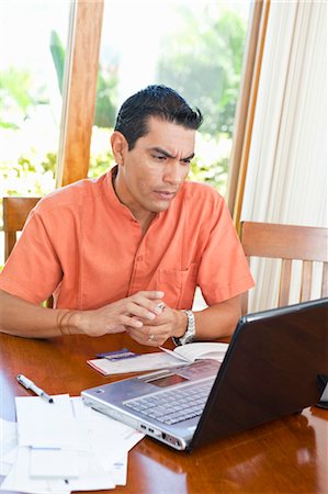 pictures of people seating on a table - man at table with bills and laptop Stock Photo - Premium Royalty-Free, Code: 673-03826405