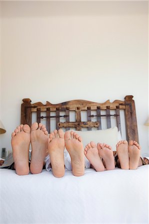 family lying on bed, feet lined up Fotografie stock - Premium Royalty-Free, Codice: 673-03826417