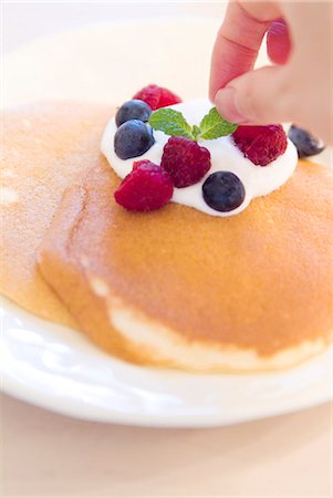 Decorating pancake with berries Stock Photo - Premium Royalty-Free, Code: 685-02937380