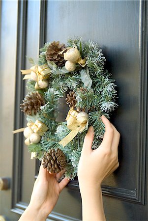 Person hanging Christmas wreath on door Stock Photo - Premium Royalty-Free, Code: 685-02937656