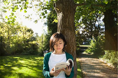 Young woman reading under a tree Stock Photo - Premium Royalty-Free, Code: 685-02937769
