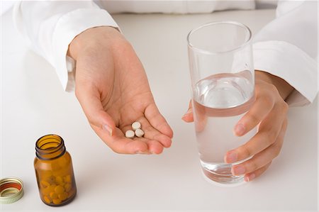 simsearch:685-02940184,k - A young woman's hand holding a glass of water and pills Foto de stock - Sin royalties Premium, Código: 685-02938557