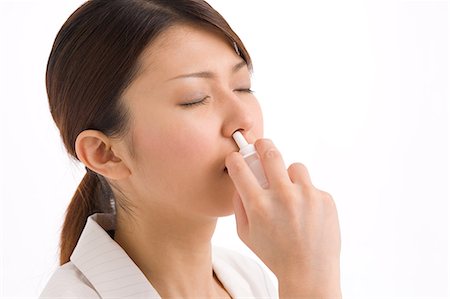 simsearch:685-02938515,k - A young woman using nasal spray Foto de stock - Royalty Free Premium, Número: 685-02938578