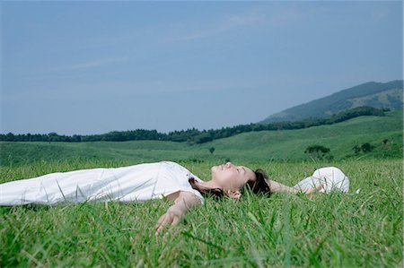 A young woman lying on grass field Stock Photo - Premium Royalty-Free, Code: 685-02938660