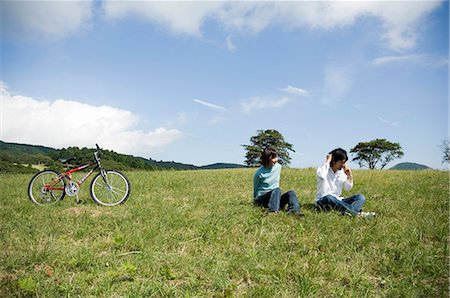simsearch:685-02939247,k - Young couple sitting on field, man using mobile phone Foto de stock - Royalty Free Premium, Número: 685-02939250