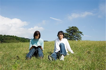 simsearch:685-02939244,k - Young couple sitting on field, woman reading book Stock Photo - Premium Royalty-Free, Code: 685-02939252