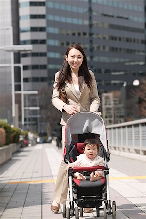 Businesswoman pushing baby stroller Stock Photo - Premium Royalty-Free, Code: 685-02939889