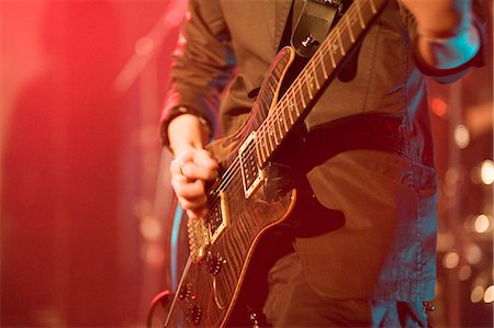 Young man playing electric guitar on stage Stock Photo - Premium Royalty-Free, Code: 685-02940338
