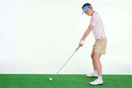 Female golfer preparing to hit golf ball Stock Photo - Premium Royalty-Free, Code: 685-02941732