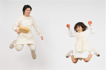 full body white background apron - Girl holding apple and father holding pan Stock Photo - Premium Royalty-Free, Code: 685-02942064