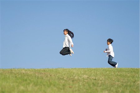 Boy and Girl jumping on grass Stock Photo - Premium Royalty-Free, Code: 685-02942098