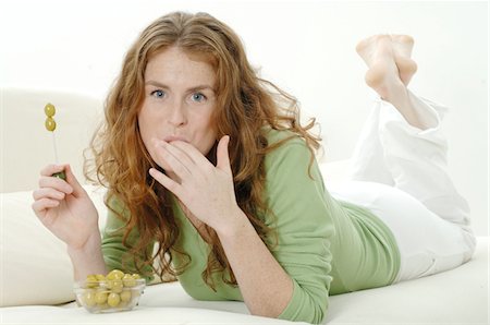 Woman lying on couch eating olives Stock Photo - Premium Royalty-Free, Code: 689-05610266