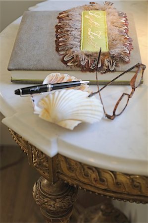 Lunettes, coquillage décoratif, plume et livre sur la table Photographie de stock - Premium Libres de Droits, Code: 689-05611853