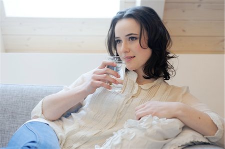 Young woman on couch drinking glass of water Stock Photo - Premium Royalty-Free, Code: 689-05611945