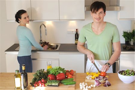 person cutting food on cutting boards - Young couple in kitchen preparing salad Foto de stock - Sin royalties Premium, Código: 689-05612001