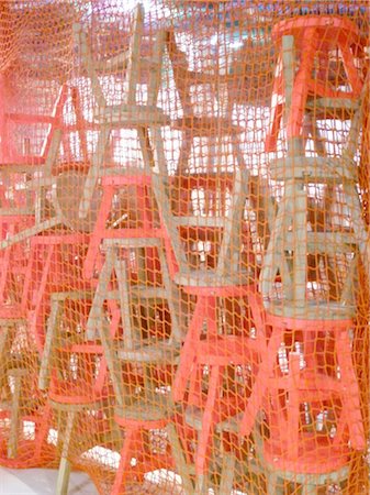 Stack of stools behind net Stock Photo - Premium Royalty-Free, Code: 689-05612192