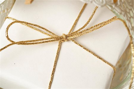 ribbon gold - White wrapped Christmas gift tied with a golden ribbon Stock Photo - Premium Royalty-Free, Code: 689-03126889