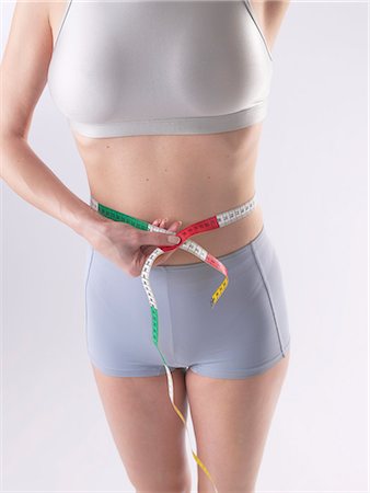 female body waist - Woman is measuring her waist Stock Photo - Premium Royalty-Free, Code: 689-03127507