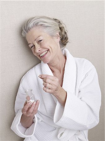 Senior adult in bathrobe holding glass of pills Stock Photo - Premium Royalty-Free, Code: 689-03129305