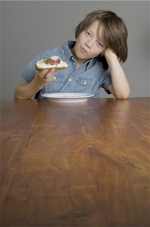 food, wooden table - Boy eating bread with cream cheese Stock Photo - Premium Royalty-Free, Code: 689-03733157