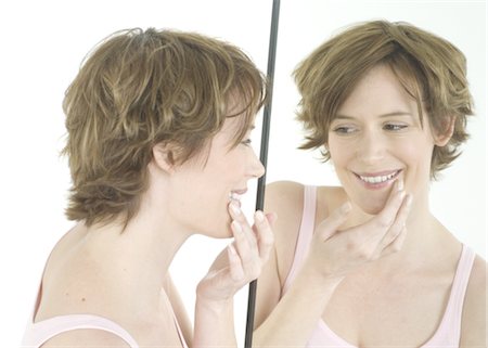 Woman looking in mirror Stock Photo - Premium Royalty-Free, Code: 689-03733249