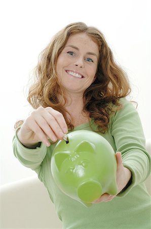 pence - Woman putting coin into piggy bank Stock Photo - Premium Royalty-Free, Code: 689-03733390