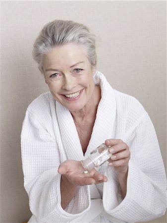senior women eating - Smiling senior woman wearing bathrobe holding medicine Stock Photo - Premium Royalty-Free, Code: 689-03733676