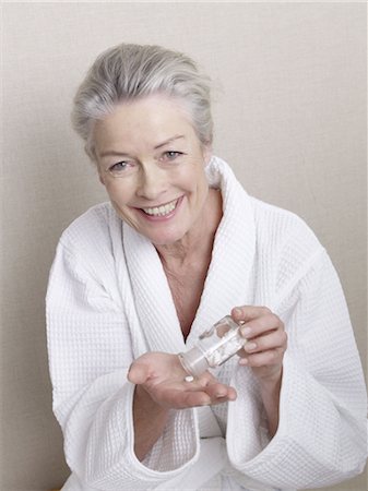 emotional feelings portrait - Smiling senior woman wearing bathrobe holding medicine Stock Photo - Premium Royalty-Free, Code: 689-03733676