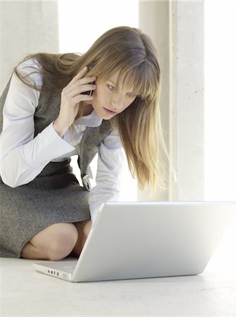 Femme d'affaires avec ordinateur portable et téléphone portable sur le plancher Photographie de stock - Premium Libres de Droits, Code: 689-03733714