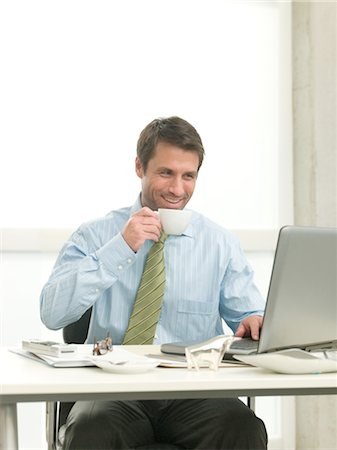 Businessman at desk drinking coffee Stock Photo - Premium Royalty-Free, Code: 689-03733759