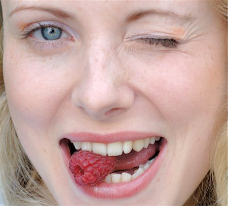 faces expression pleasure - Woman eating raspberry Stock Photo - Premium Royalty-Free, Code: 689-03733802