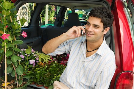 simsearch:694-03692195,k - Man sitting by flowers on back of minivan using cell phone Stock Photo - Premium Royalty-Free, Code: 694-03318090