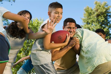 friends playing football - Boy (13-15) playing football with family. Stock Photo - Premium Royalty-Free, Code: 694-03318174