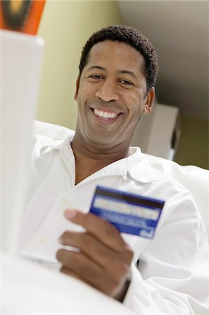 paying with black card - Man on sofa  Using Credit Card to Make Purchase with Laptop, portrait, low angle view Stock Photo - Premium Royalty-Free, Code: 694-03318512