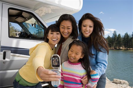 Three-generations of women photographing selves outside RV at lake Stock Photo - Premium Royalty-Free, Code: 694-03318641