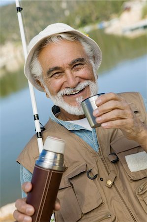 portrait fisherman older - Middle-aged man fishing, holding vacuum flask, smiling, (portrait) Stock Photo - Premium Royalty-Free, Code: 694-03318953