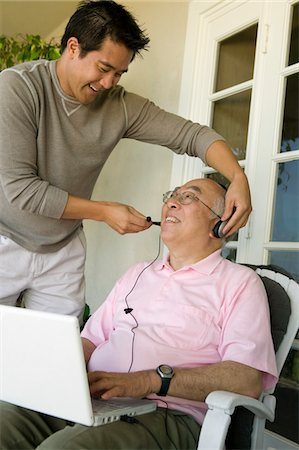 Son adjusting headset on father's head Stock Photo - Premium Royalty-Free, Code: 694-03318975