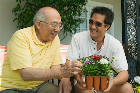 simsearch:694-03318999,k - Man holding potted plant, talking to father in garden Fotografie stock - Premium Royalty-Free, Codice: 694-03318988