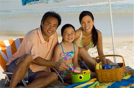 summertime picnic with family in the beach - Parents with daughter (7-9) having picnic on beach, (portrait) Stock Photo - Premium Royalty-Free, Code: 694-03319454