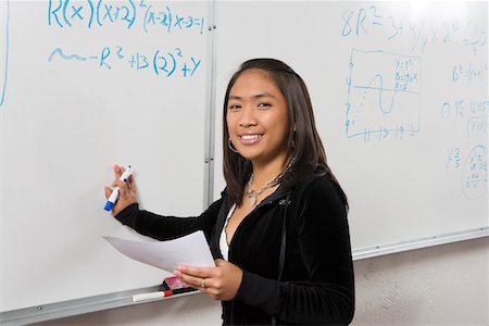 Female student writing maths equations on whiteboard Stock Photo - Premium Royalty-Free, Code: 694-03319678