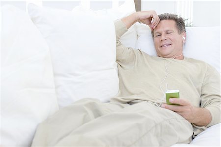 Middle-aged man listening to music on sofa Stock Photo - Premium Royalty-Free, Code: 694-03324164
