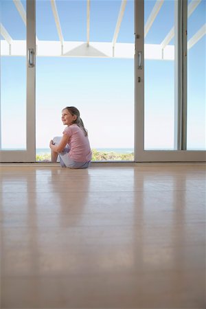 Girl sitting on floor in doorway, smiling Stock Photo - Premium Royalty-Free, Code: 694-03326217