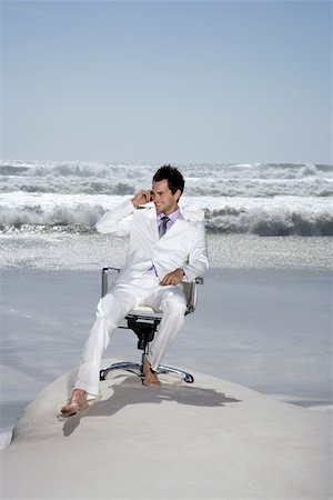 Man using mobile phone sitting on office chair on beach Stock Photo - Premium Royalty-Free, Code: 694-03326248