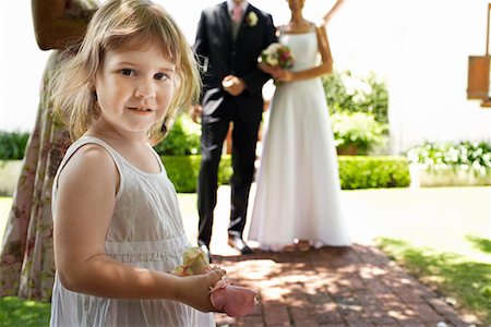 Jeune fille tenant des pétales de fleurs, mariée et le marié debout en arrière-plan Photographie de stock - Premium Libres de Droits, Code: 694-03326457