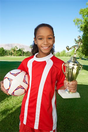 Girl (7-9 years) soccer player holding trophy and ball, portrait Foto de stock - Royalty Free Premium, Número: 694-03327031