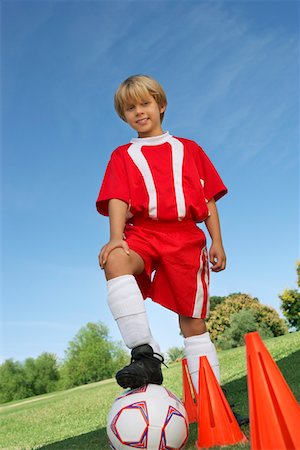 Boy (7-9 years) soccer player holding foot on ball, portrait Stock Photo - Premium Royalty-Free, Code: 694-03327040