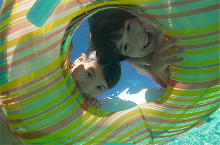 Boy and girl looking through inflatable raft in swimming pool, underwater view Stock Photo - Premium Royalty-Free, Code: 694-03327201